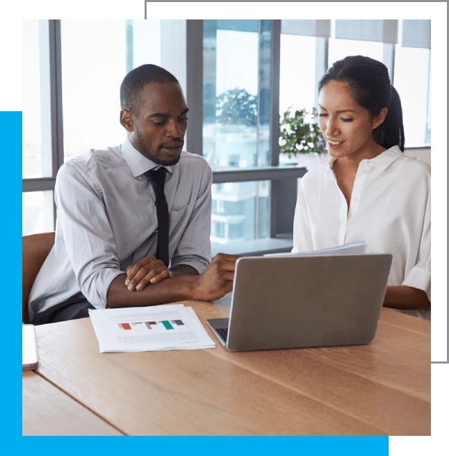 Two people sitting at a table looking at a laptop.